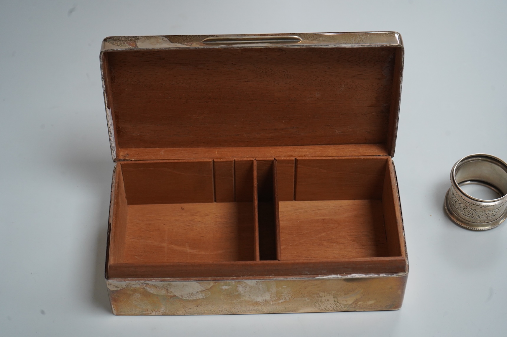 A George VI silver mounted rectangular cigarette box, Atkin Brothers, London, 1944, 17.3cm, together with a small silver dish, William Comyns & Sons Ltd, London, 1945, an Edwardian silver napkin ring and a George III sil